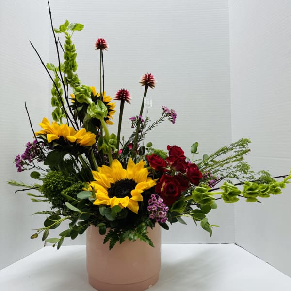 Sunflower and red rose arrangement in a blush cylindrical vase