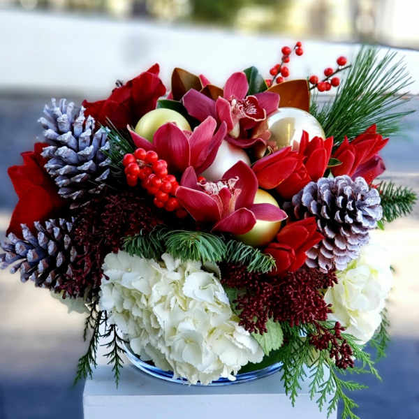 Holiday bouquet with red flowers, white hydrangeas, pinecones, and ornaments