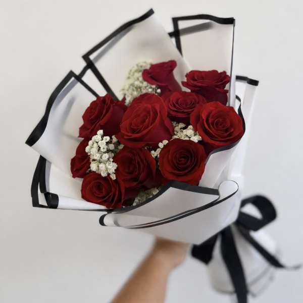 Bouquet of red roses wrapped in white paper with black trim