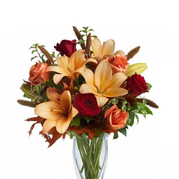 Bouquet of peach lilies and red roses in a clear glass vase