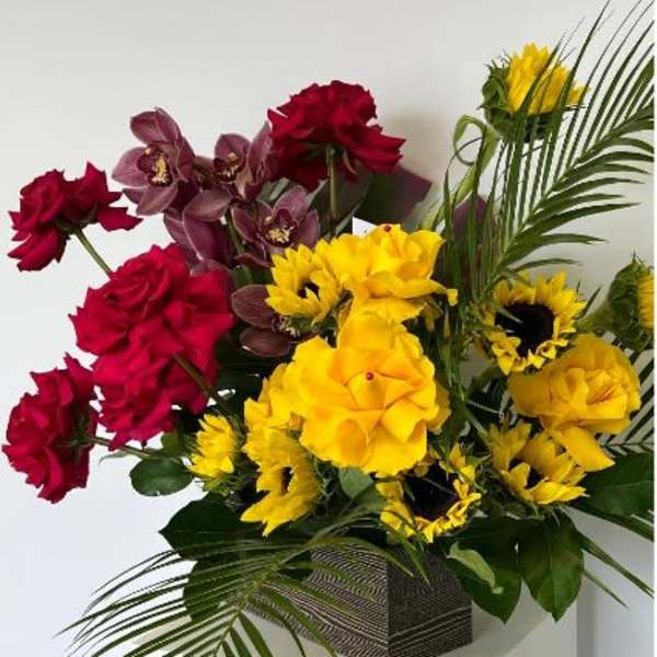 Red and yellow floral arrangement in a square vase