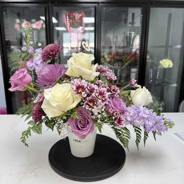 Lavender and cream rose bouquet in a white vase