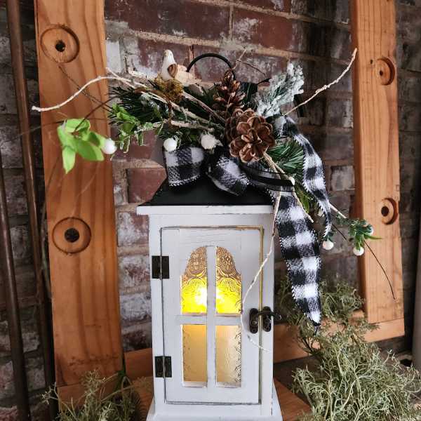 Decorative lantern with pinecones, plaid ribbon, and greenery