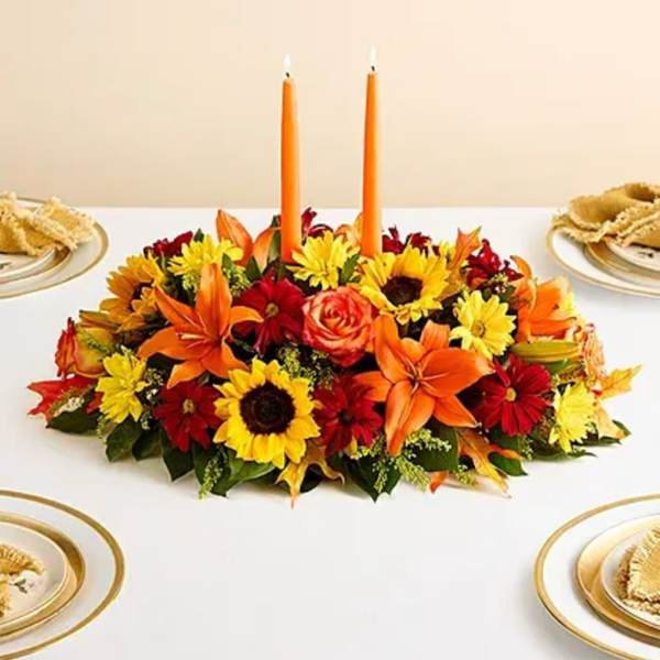 Low floral centerpiece with orange candles and mixed autumn blooms