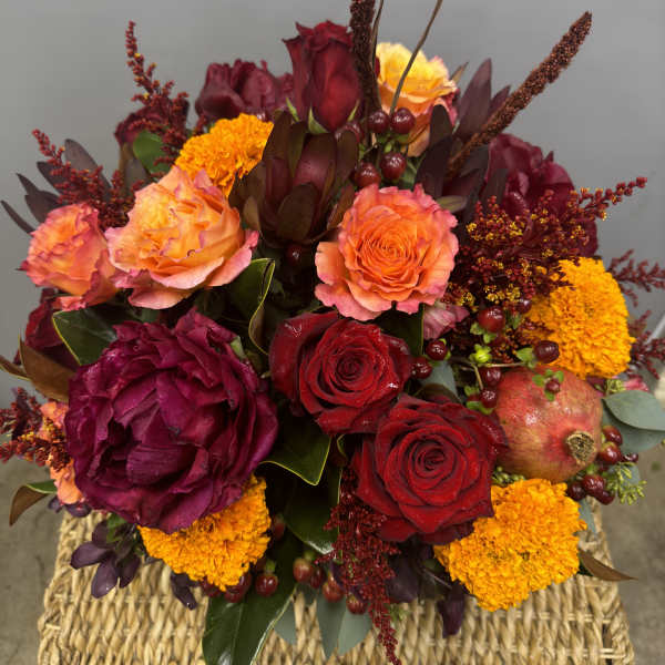 Mixed bouquet of red and orange roses with marigolds in a woven basket