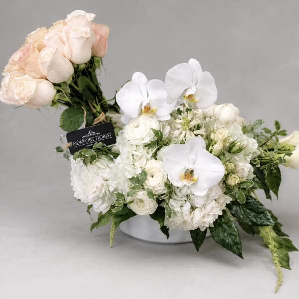 White and blush floral arrangement in a low vase with orchids and roses