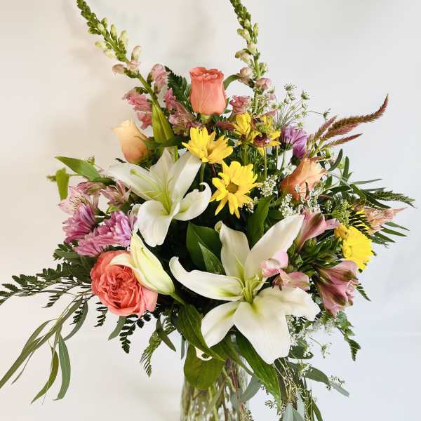 Mixed bouquet of lilies, roses, and daisies in a glass vase