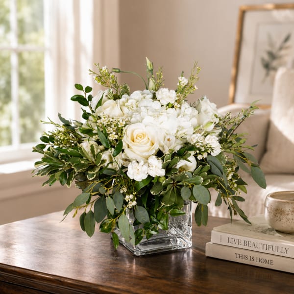 White roses and hydrangeas in a clear square vase