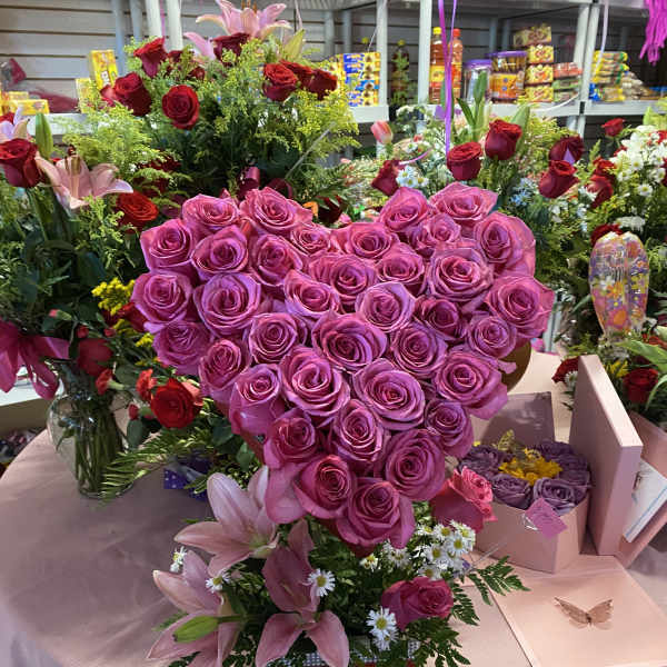Heart-shaped bouquet of pink roses with lilies and small white daisies