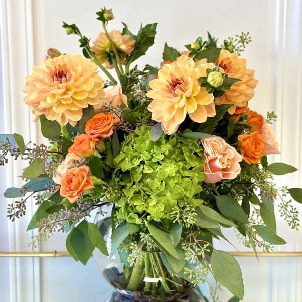 Bouquet of peach dahlias and orange roses in a glass vase