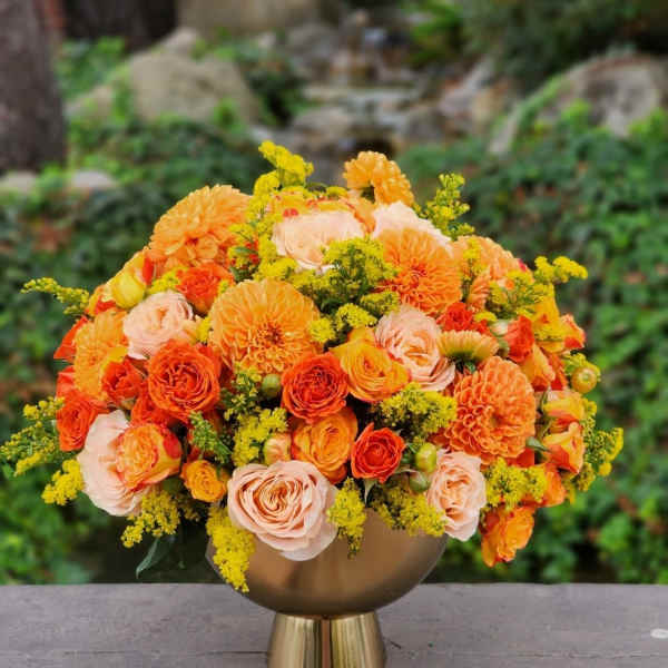 Orange and peach bouquet in a gold vase