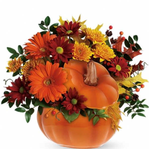 Fall bouquet in a pumpkin-shaped container with orange and red flowers