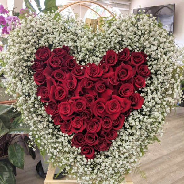 Heart-shaped red rose arrangement surrounded by white baby's breath