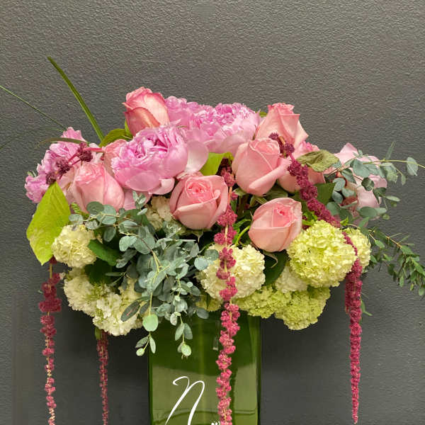 Pink roses and peonies in a tall green glass vase