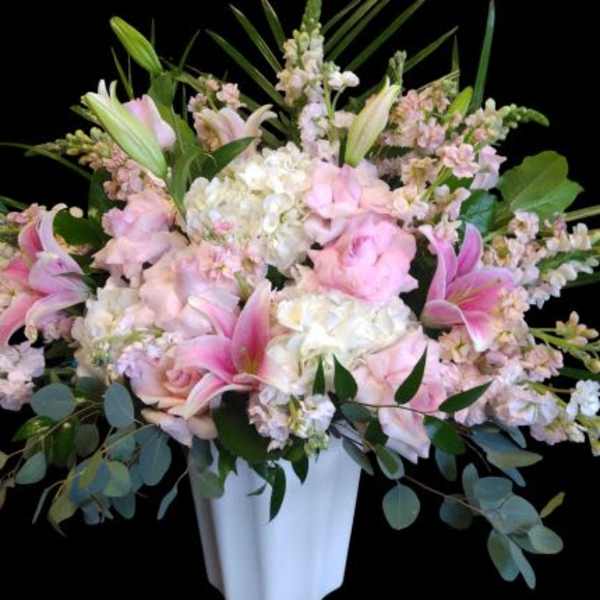 Pink lilies and pale roses in a white vase