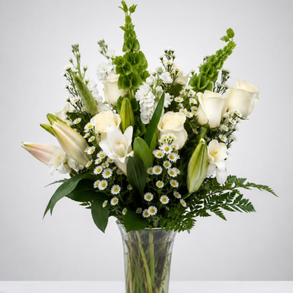 White roses and lilies arranged in a clear glass vase