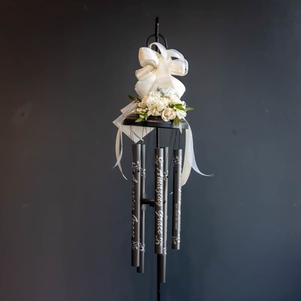 White floral topper with ribbon on a black wind chime stand