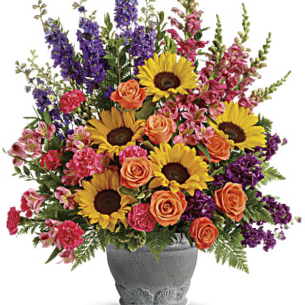 Colorful bouquet of sunflowers, roses, and purple flowers in a gray vase