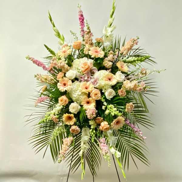 Large standing floral spray with peach and white blooms and palm fronds