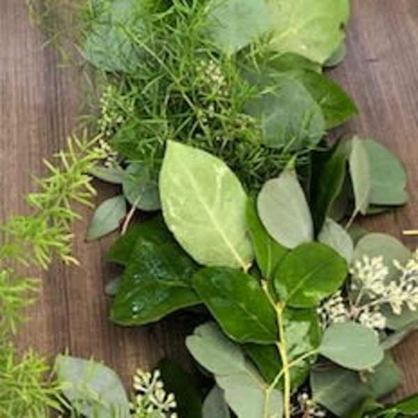 Loose garland of assorted green foliage on a wooden surface