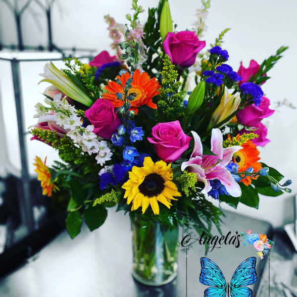 Mixed bouquet of roses, lilies, and sunflowers in a glass vase