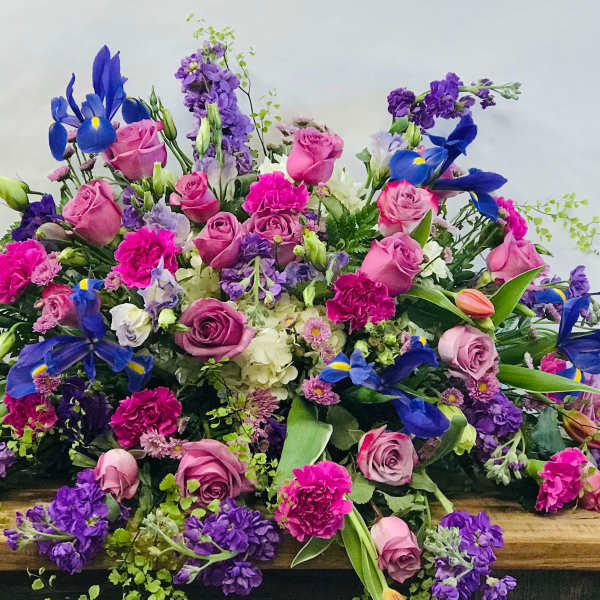 Large mixed bouquet of pink, purple, and blue flowers on a wooden surface