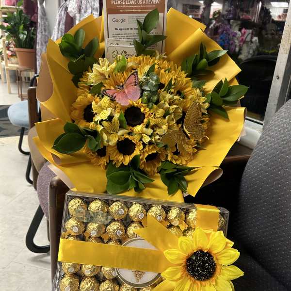 Sunflower bouquet with yellow wrapping and a box of chocolates tied with ribbon