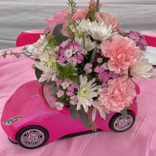 Pink and white bouquet arranged in a pink toy car