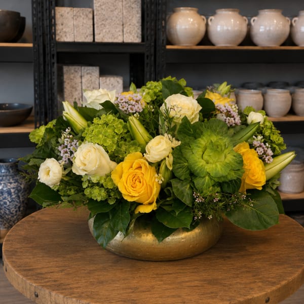 Yellow and white roses arranged in a gold bowl vase