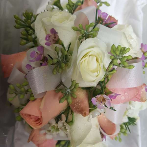 Small bouquet of white and blush roses with purple accents and ribbon