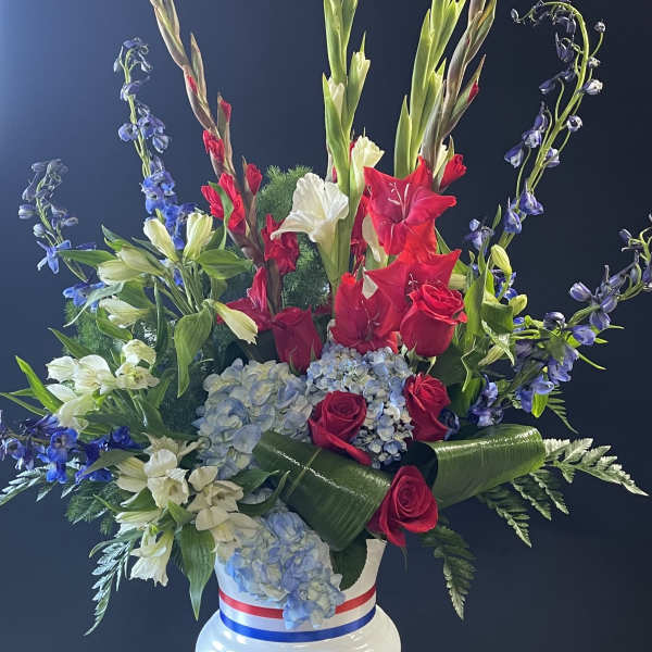Tall red, white, and blue floral arrangement in a white vase