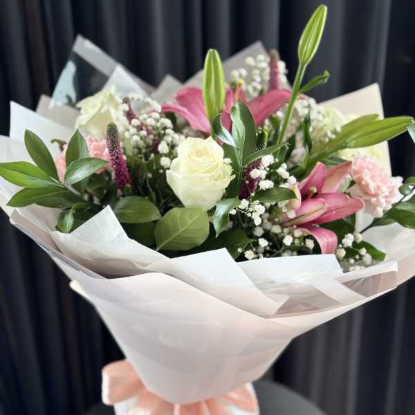 Bouquet of pink lilies and white roses wrapped in white paper
