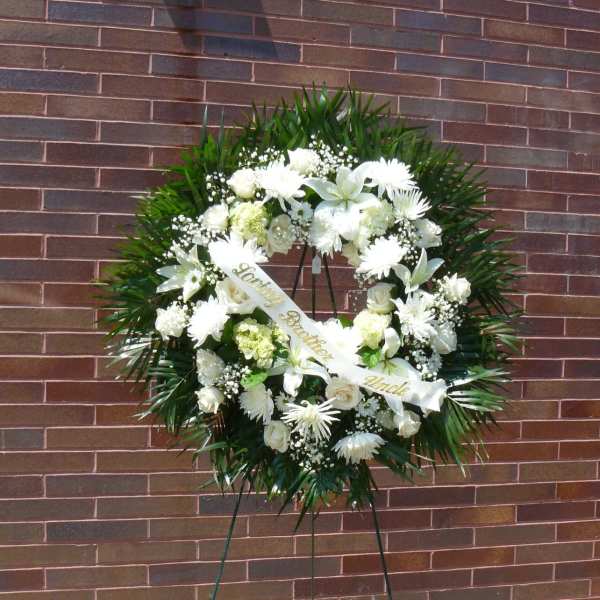 White funeral wreath on a stand with a ribbon