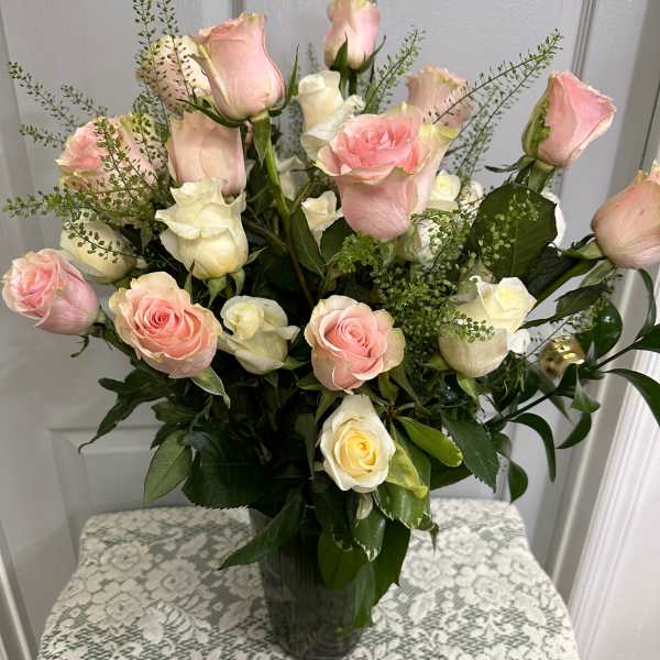 Pink and white roses arranged in a clear glass vase