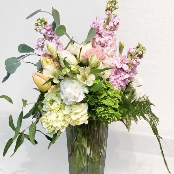Pastel floral arrangement in a tall glass vase with pink and white blooms