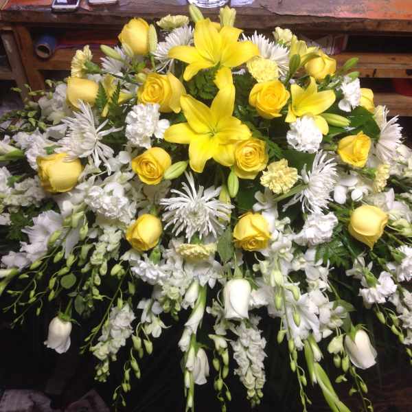 Yellow lilies and roses arranged with white flowers in a large spray