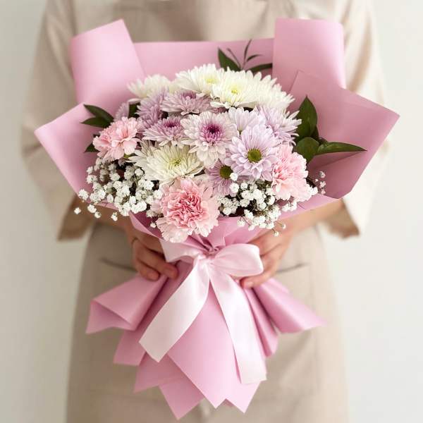 Pink-wrapped bouquet of pastel chrysanthemums with a white ribbon