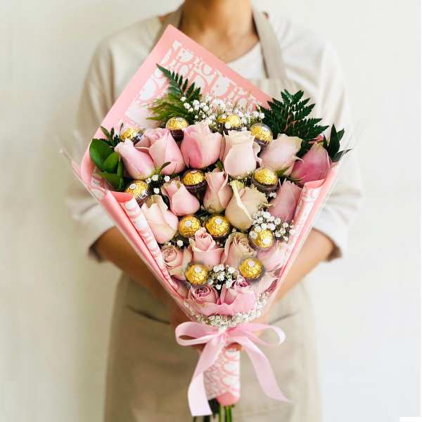 Pink rose bouquet with gold-wrapped chocolates and a pink ribbon