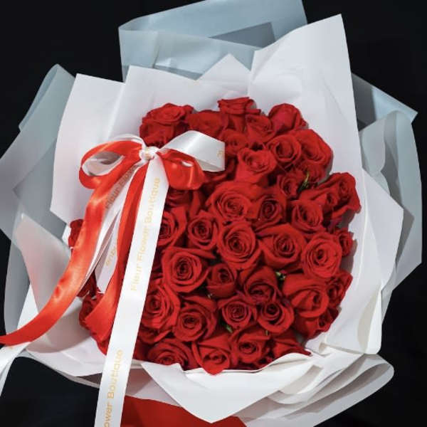 Bouquet of red roses wrapped in white paper with a red ribbon