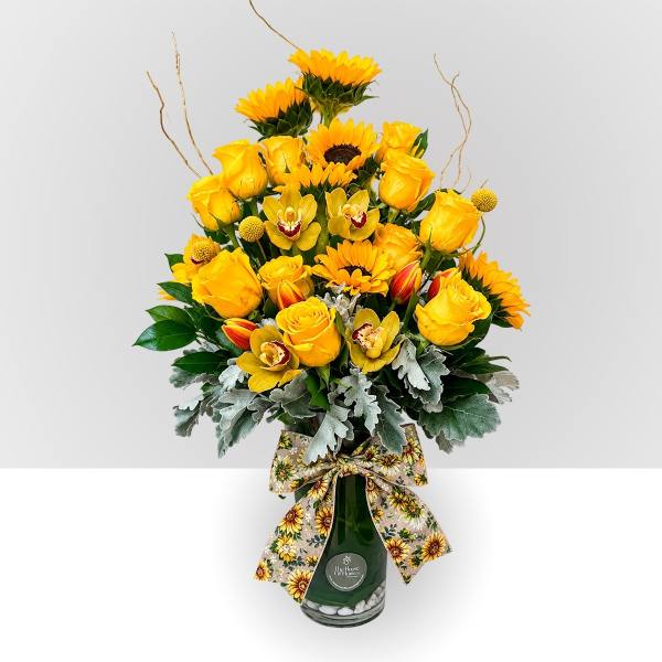 Yellow roses and sunflowers in a green glass vase with a sunflower ribbon