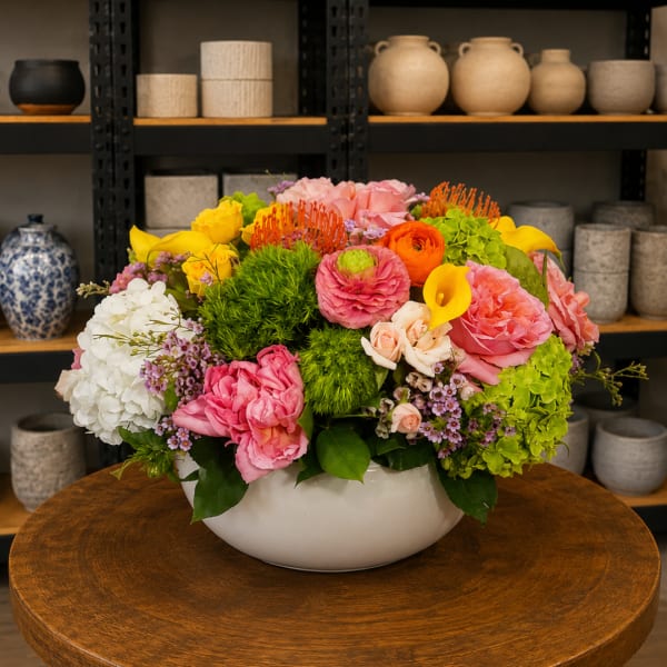 Colorful mixed flower arrangement in a white bowl vase