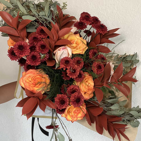 Bouquet of orange roses and burgundy mums with dried foliage