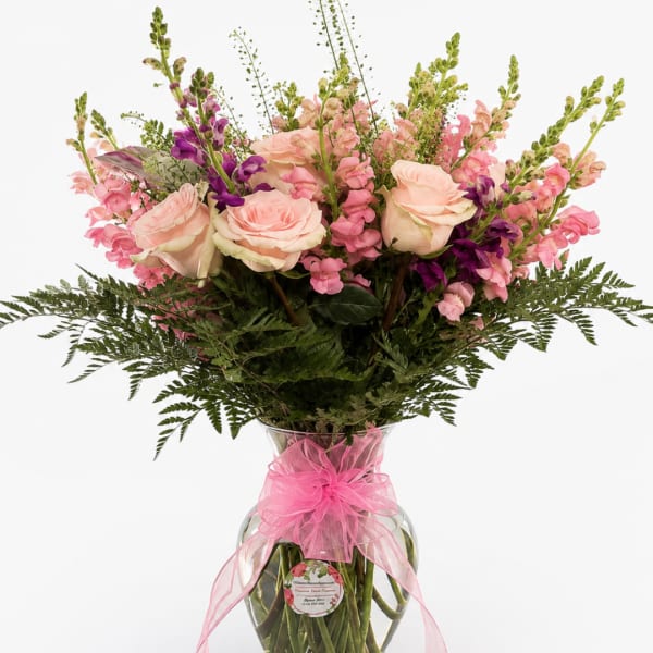 Pink and peach roses with snapdragons in a glass vase tied with a pink bow