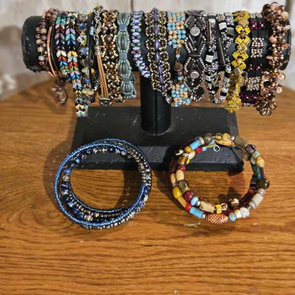 Display stand holding multiple beaded bracelets on a wooden surface