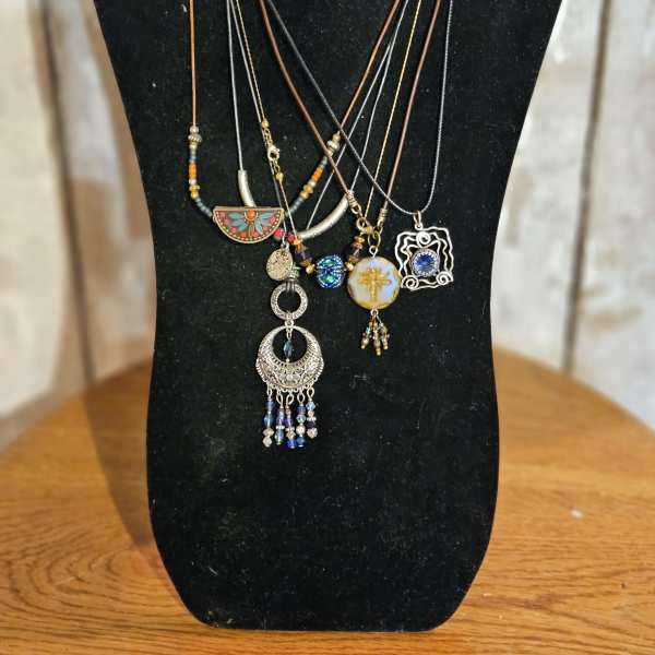 Layered pendant necklaces on a black display bust