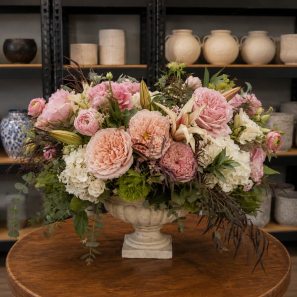 Pink and peach floral arrangement in a pedestal vase