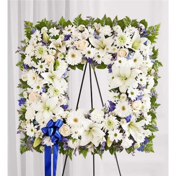 Large white floral wreath on a black stand with a blue ribbon