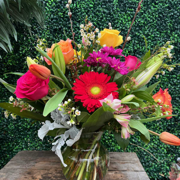 Mixed bouquet in a clear glass vase with roses, gerbera daisies, tulips, and lilies