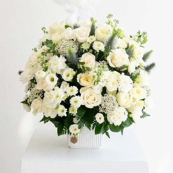 White roses and mixed white flowers in a ribbed white vase