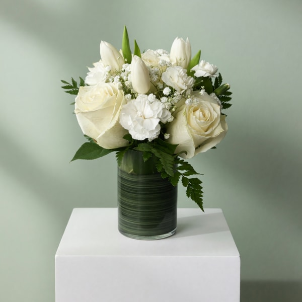 White roses and tulips arranged in a glass vase